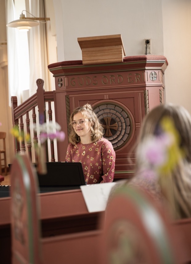 Pianist ved flygel foran publikum i kirkerum.