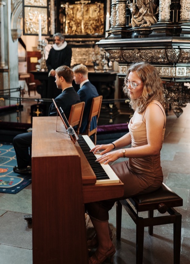 Pianist spiller til vielse i et stemningsfuldt kirkerum.